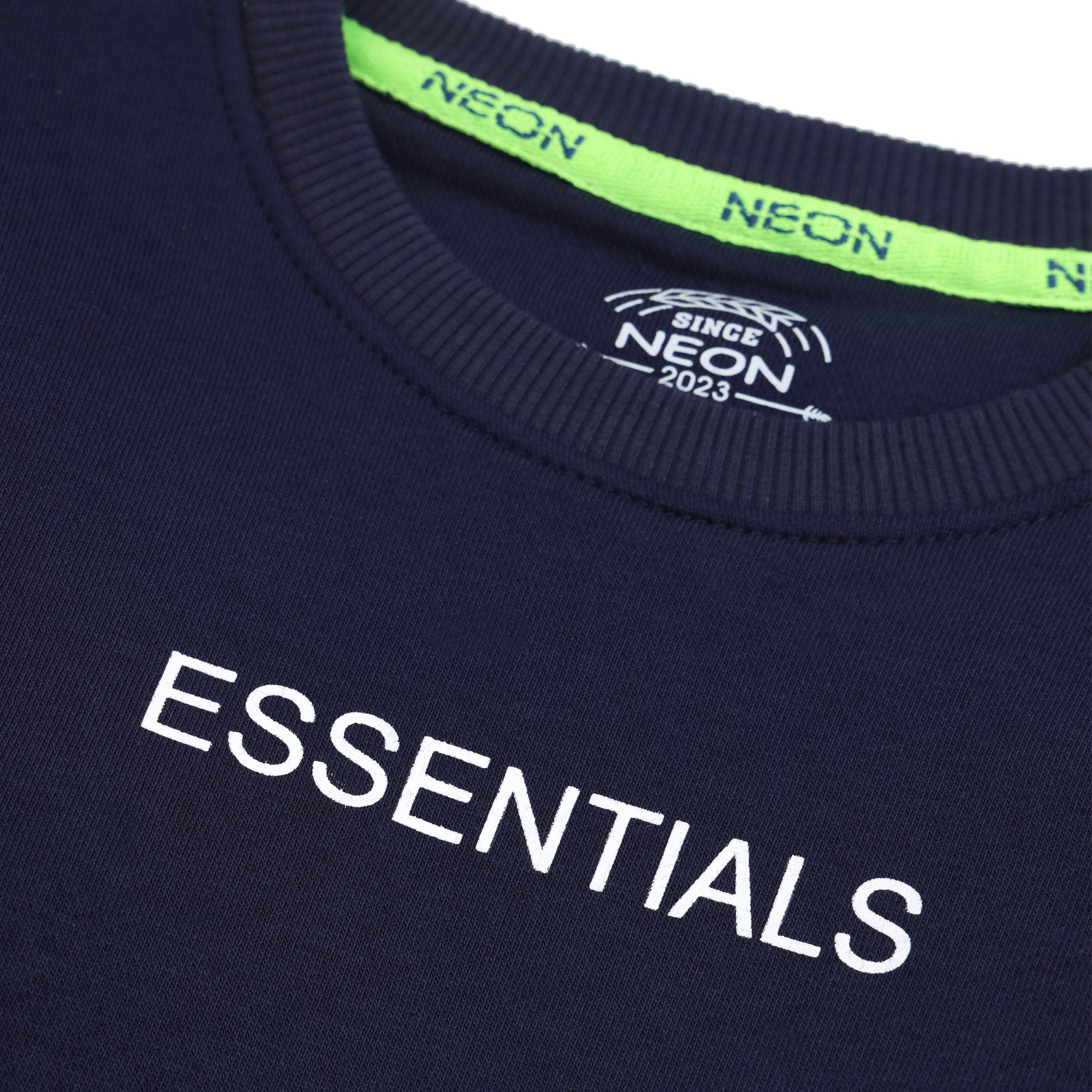 Close-up of the white Essentials chest print and neon green branded neck tape on the navy boys’ sweatshirt.