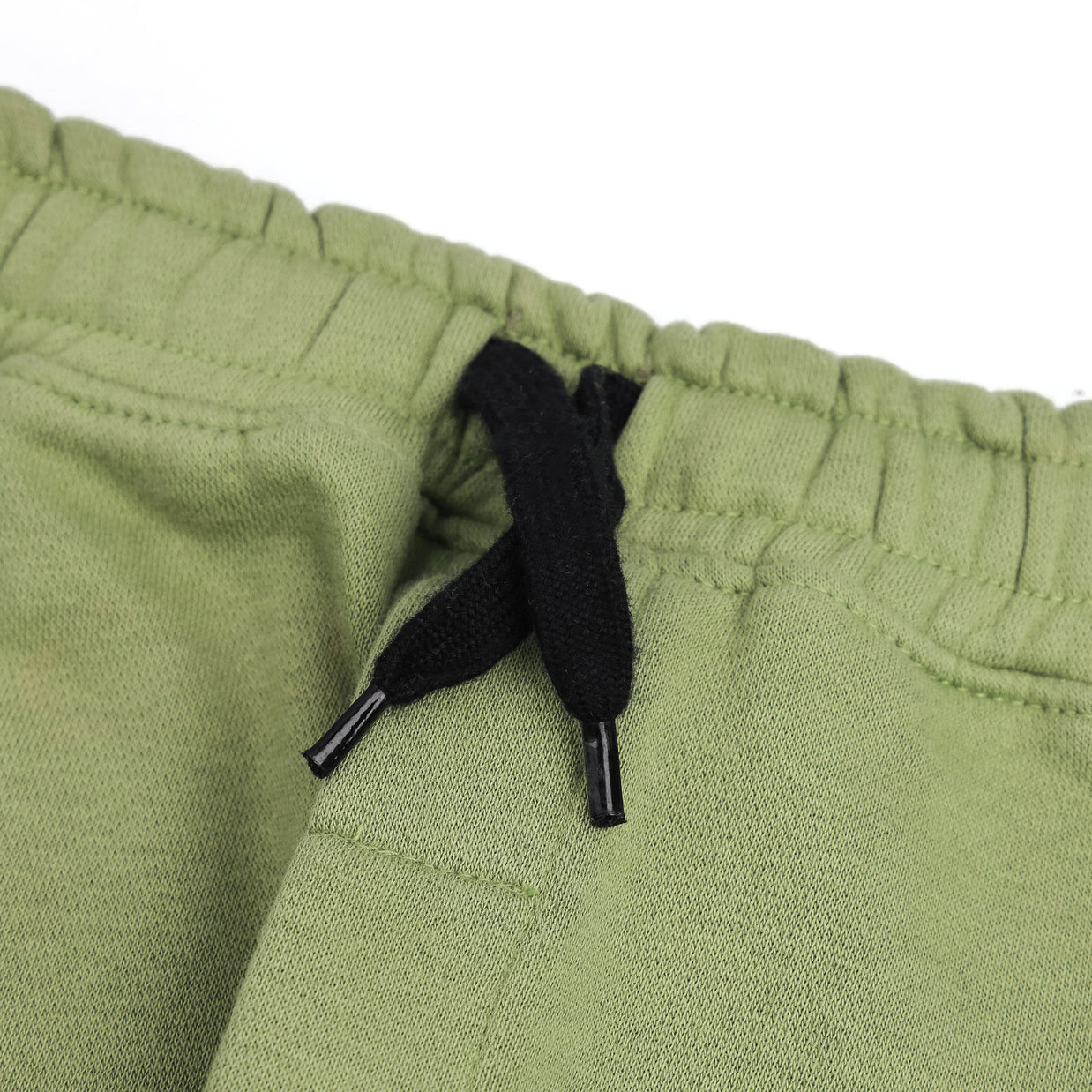 Close-up of the elasticated waistband and contrast black drawstring on the boys sage green fleece joggers.