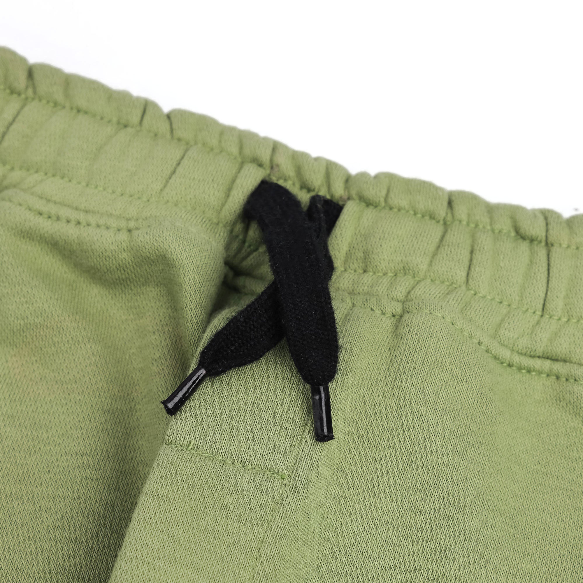 Close-up of the elasticated waistband and contrast black drawstring on the boys sage green fleece joggers.
