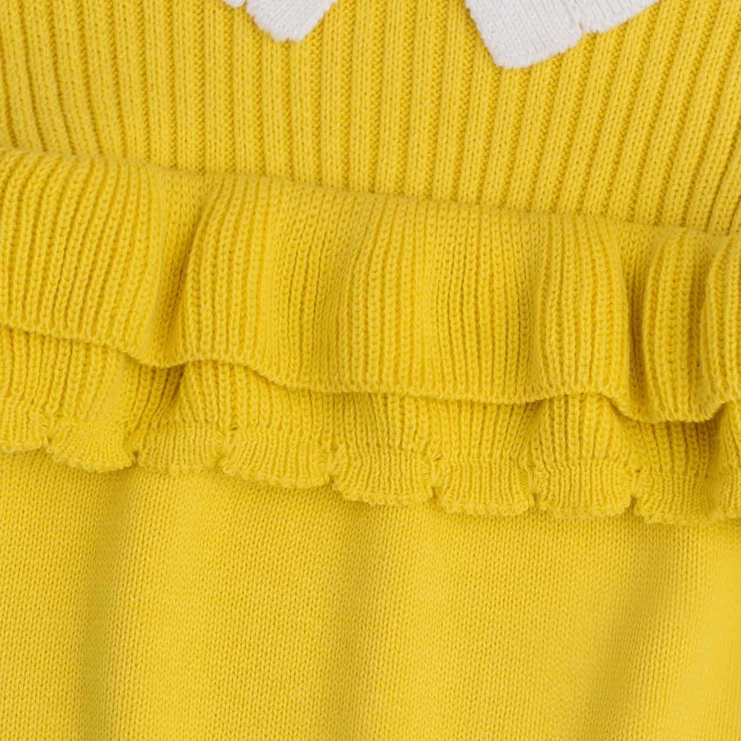 Close-up view of the layered yellow ruffle details, ribbed texture and white scalloped collar on the girls cotton sweater.