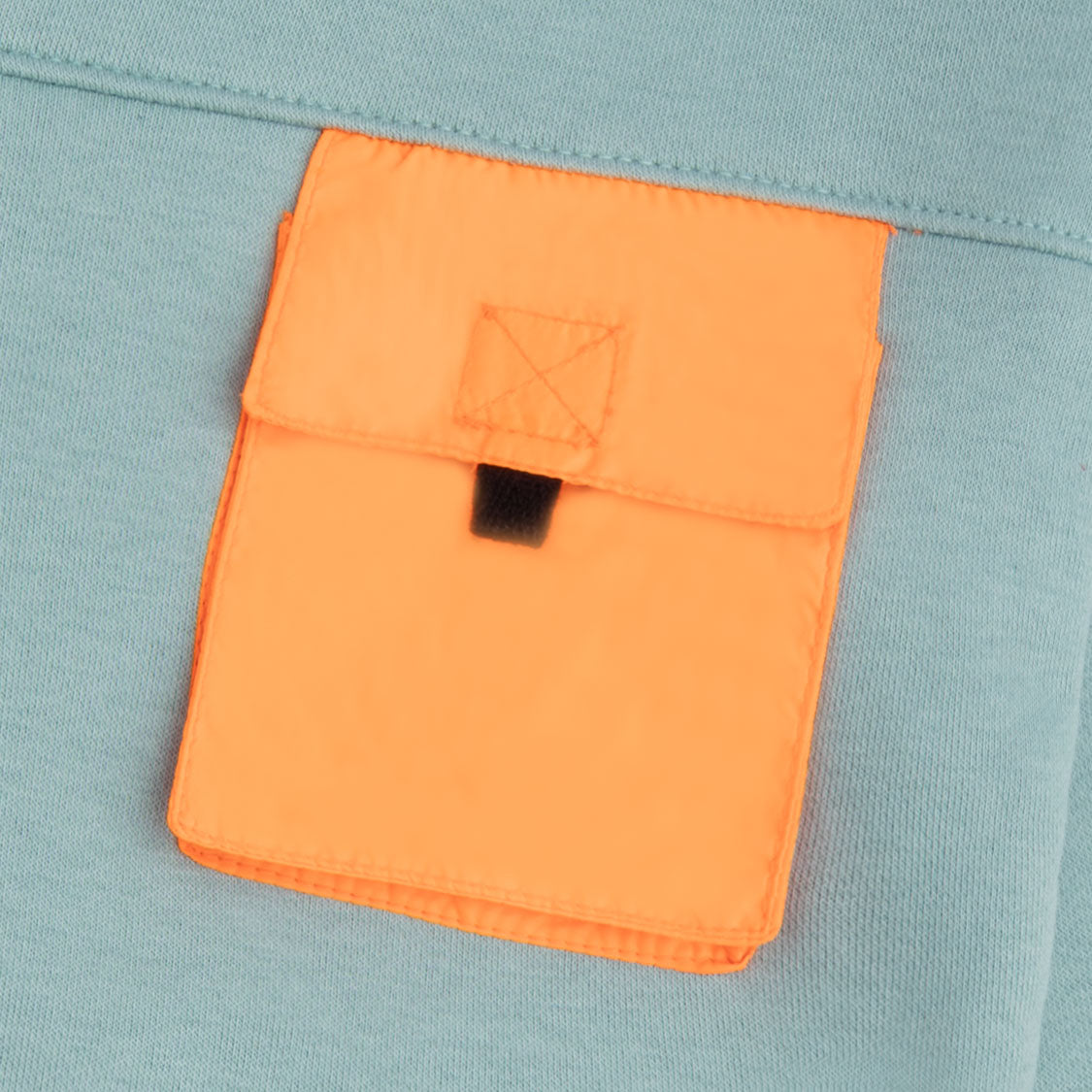 Close-up of the orange flap chest pocket and black pull tab on the boys dusty blue fleece sweatshirt.
