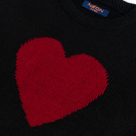 Close-up view of the bold red heart design and soft black cotton texture on the girls crew neck sweater.
