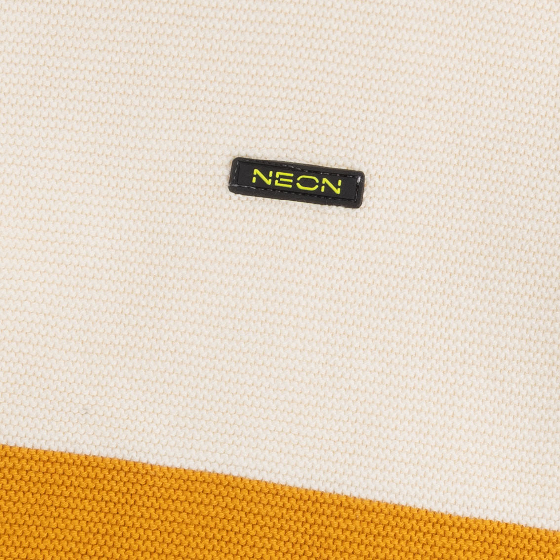 Close-up view of the off-white and mustard cotton texture with the contrast NEON logo detail on the boys color block sweater.