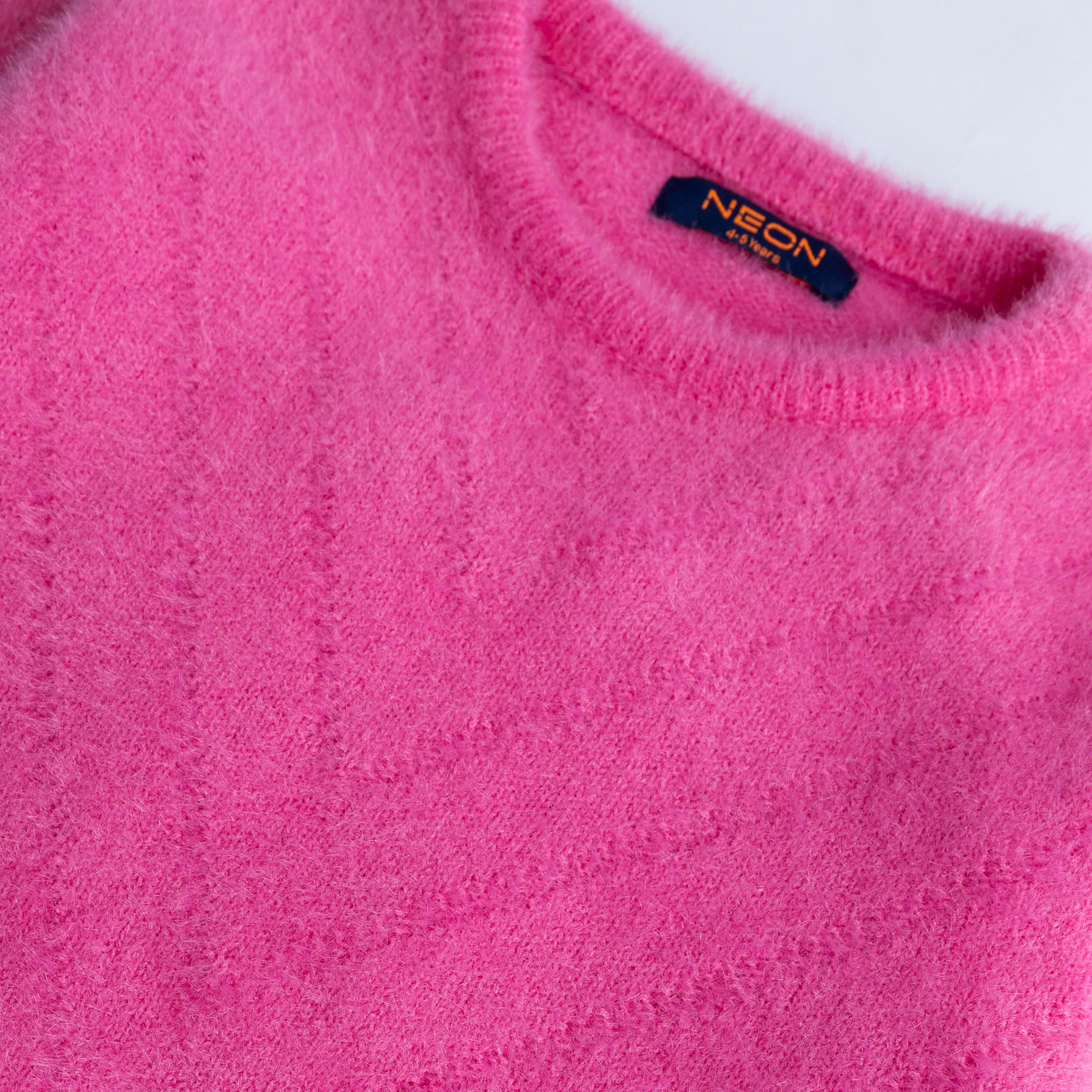 Close-up view of the ultra-soft and fluffy bright pink feather yarn texture on the girls crew neck sweater.