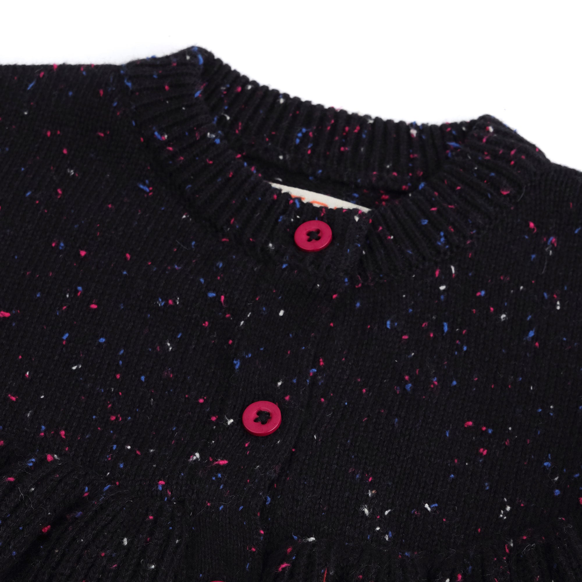 Close-up view of the girls black cotton cardigan, showing its ribbed neckline, pink buttons and fine pink, blue and white speckled knit detailing.