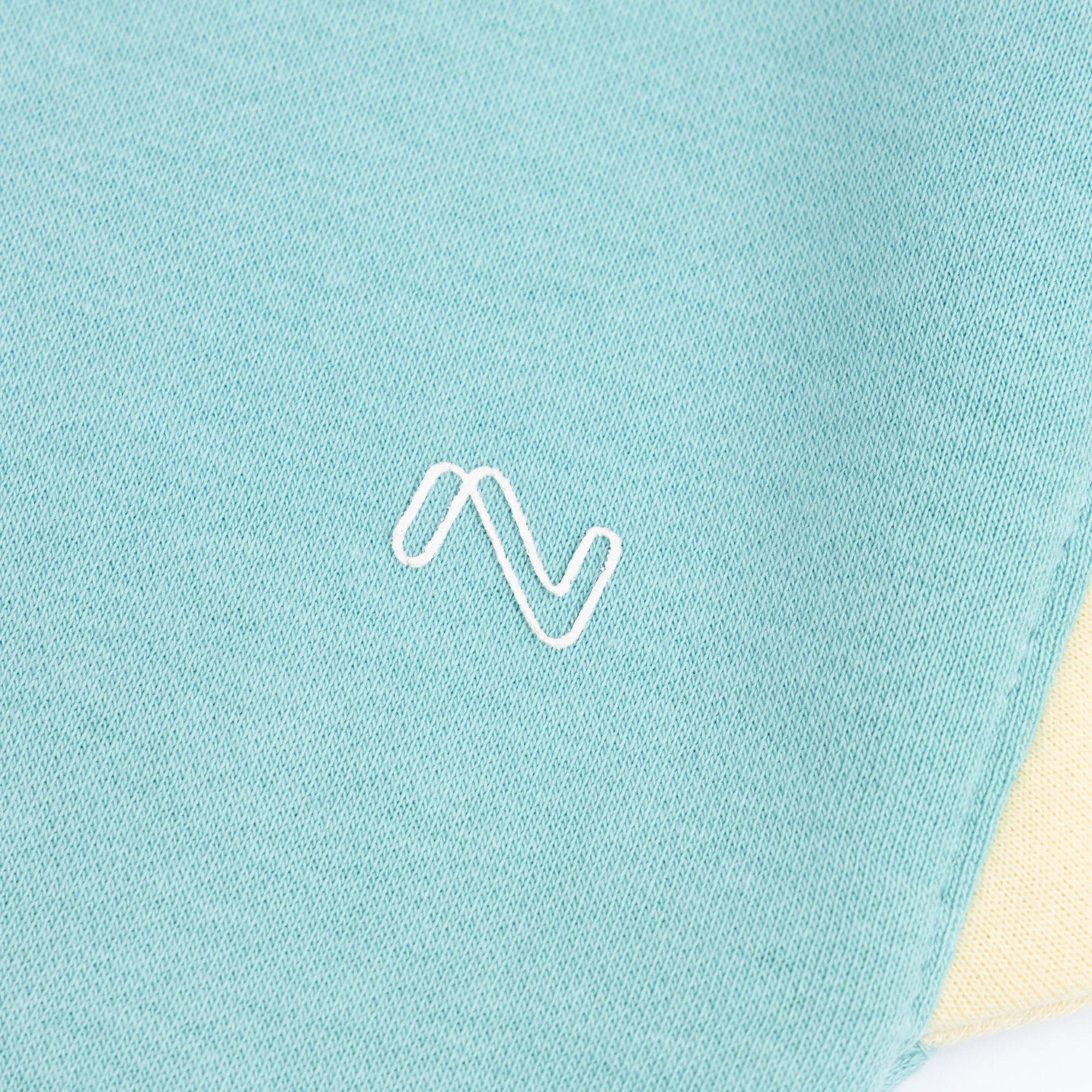 Close-up of the white embroidered chest logo on the aqua blue fleece sweatshirt for kids.