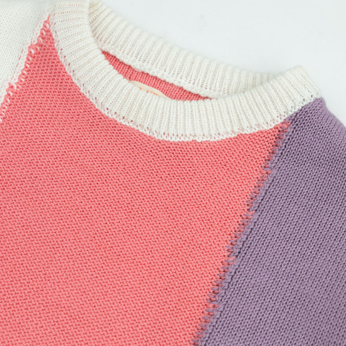 Close-up of the girls Pastel Color Block Sweater showing its soft cotton knit, contrast stitching and white, coral pink and lavender sections.