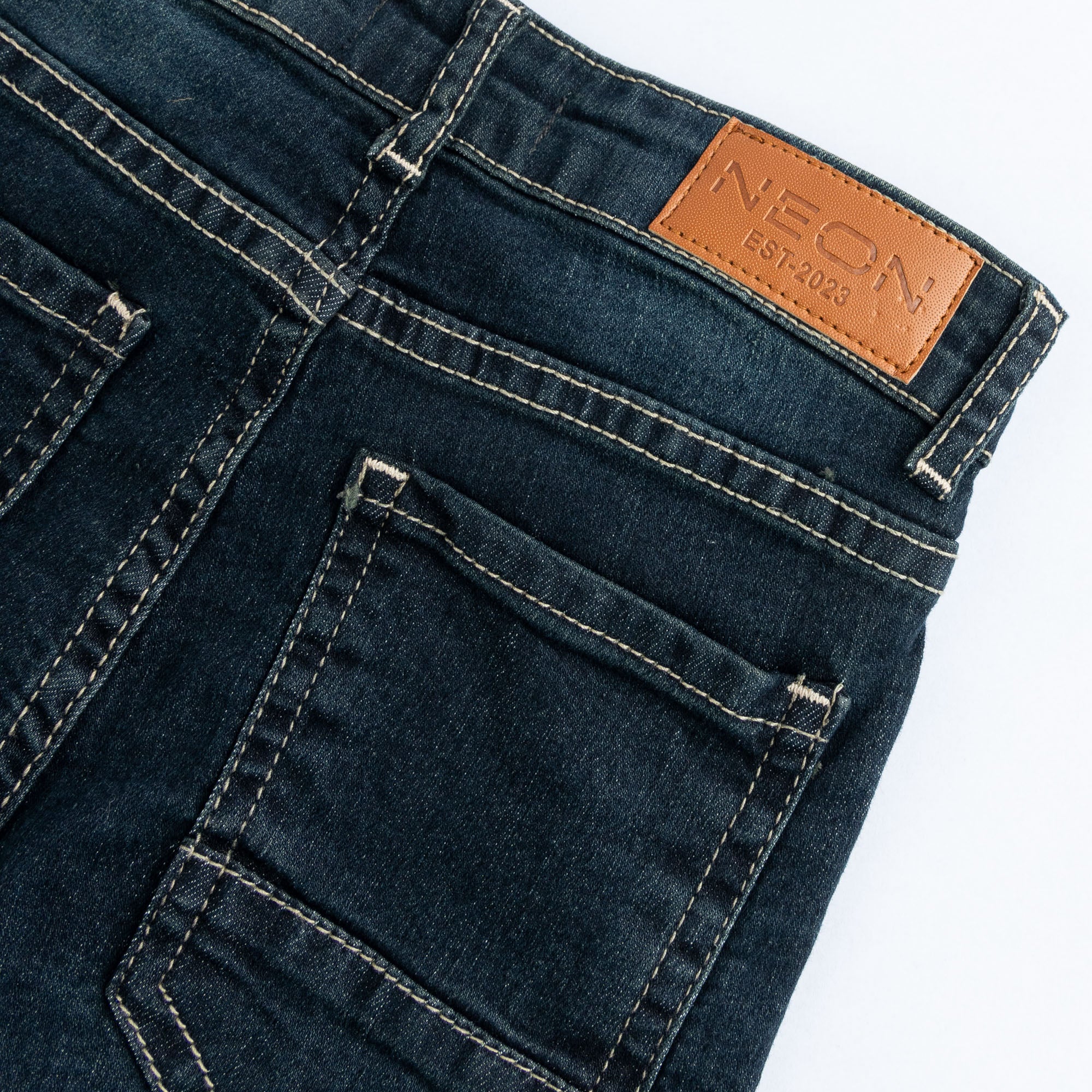 Close-up of the back pocket, contrast stitching and branded tan waist patch on the kids vintage dark wash denim.