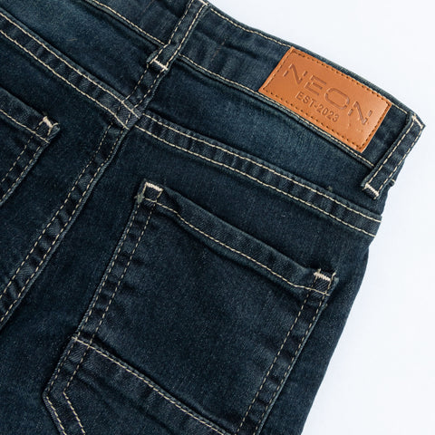 Close-up of the back pocket, contrast stitching and branded tan waist patch on the kids vintage dark wash denim.