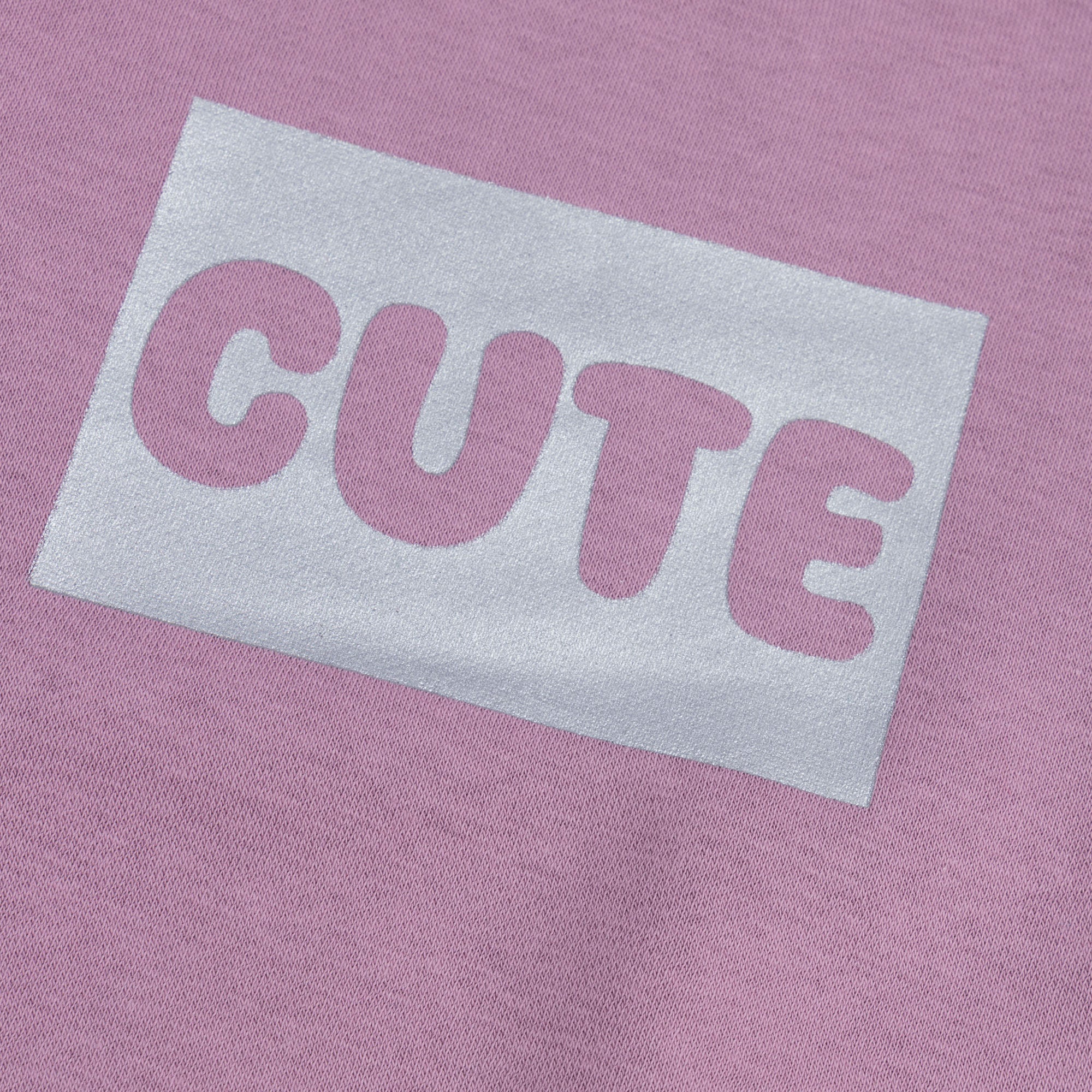 Close-up view of the white CUTE graphic printed on the soft dusty pink fleece sweatshirt from the girls co-ord set.