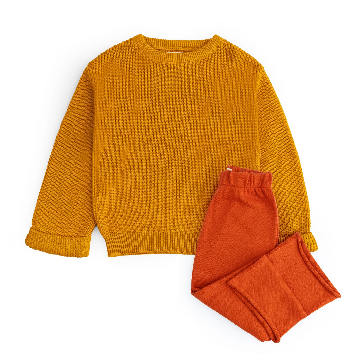 Girls two-piece knitted cotton co-ord set featuring a textured mustard crew neck top with folded cuffs and rust orange elastic-waist trousers.