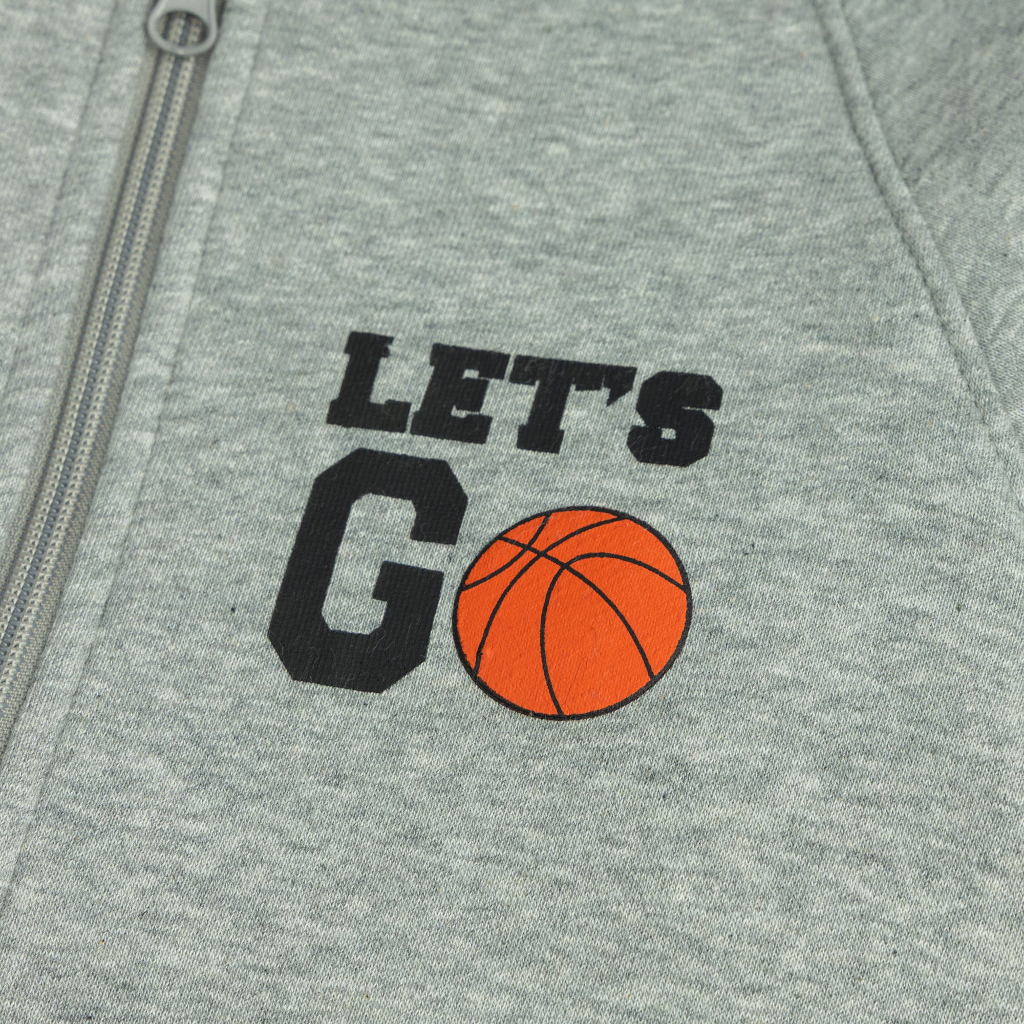 Close-up of the black “Let’s Go” text and orange basketball graphic on the grey zip jacket.