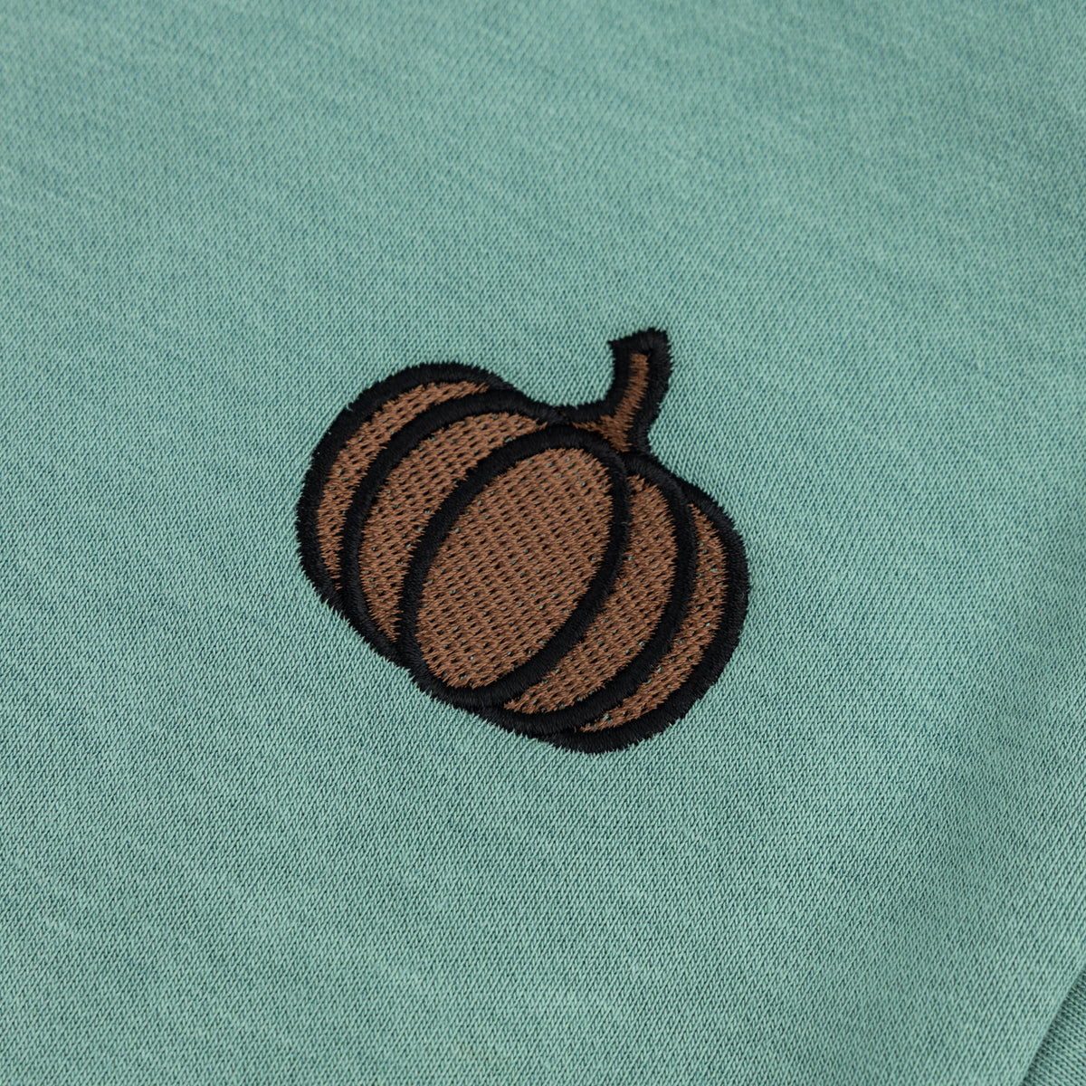 Close-up of the brown and black embroidered pumpkin detail on the mint green boys’ sweatshirt.