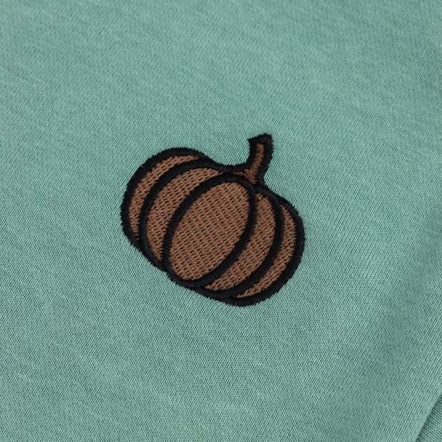 Close-up of the brown and black embroidered pumpkin detail on the mint green boys’ sweatshirt.