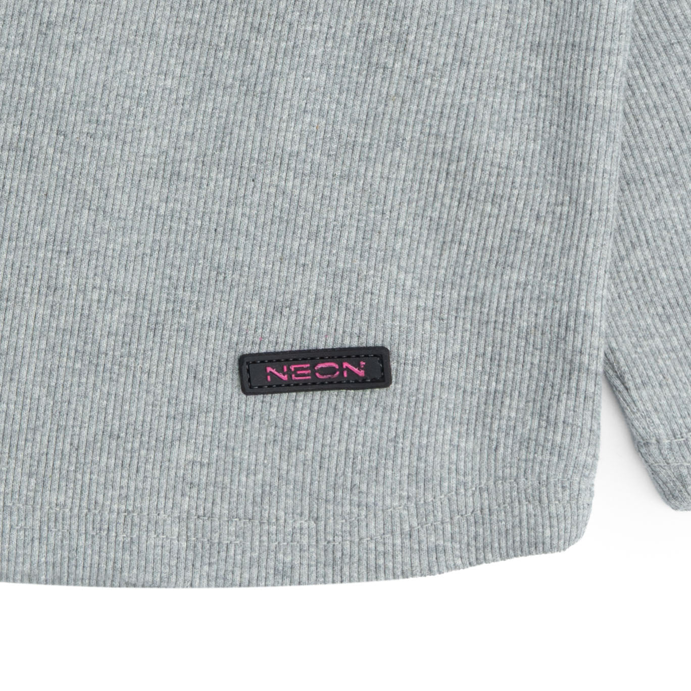 Close-up view of the soft light grey ribbed fabric and contrast pink NEON logo detail on the girls long-sleeve co-ord top.
