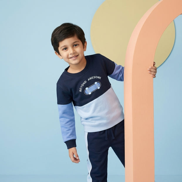 Smiling young boy wearing a navy and light-blue Color Block Co-ord Set with matching drawstring joggers.