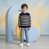 Young boy wearing a navy and cream striped crew-neck sweater paired with light-wash denim.