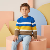 Young boy wearing a multicolor striped sweater paired with light-wash denim.