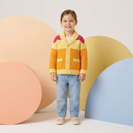 Young girl wearing a yellow, orange and pink color-block button-down cardigan with a wide collar and front pockets.