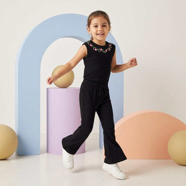 Girl wearing a black Floral Rib Co-ord Set featuring a sleeveless embroidered top and matching flared trousers.