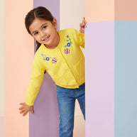 Young girl wearing a yellow button-front cardigan with floral and butterfly embroidery, paired with blue denim.
