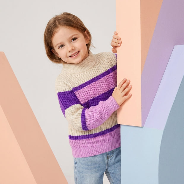 Young girl wearing a cream, purple and pink striped mock-neck sweater paired with light-wash denim.