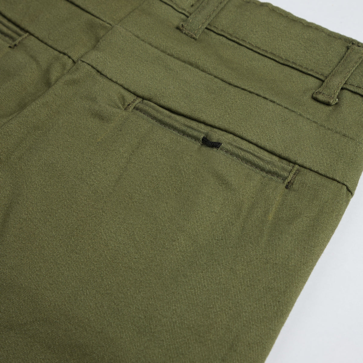 Close-up of the back welt pocket, belt loops and smooth twill texture on the kids’ olive green pants.